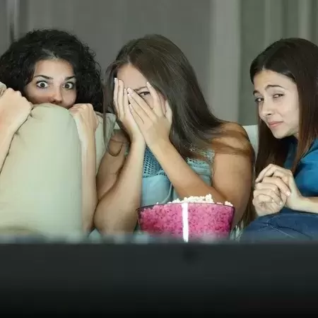 Three women watching a scary Halloween movie 