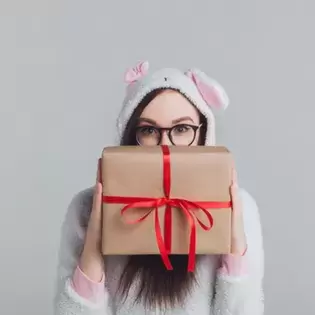 A girl in an animal costume holding a wrapped gift 