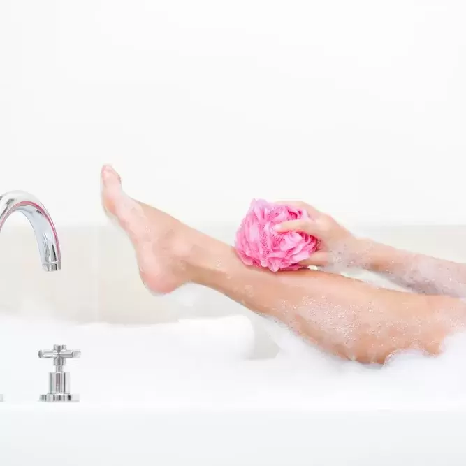 person taking a bath and using a loofah