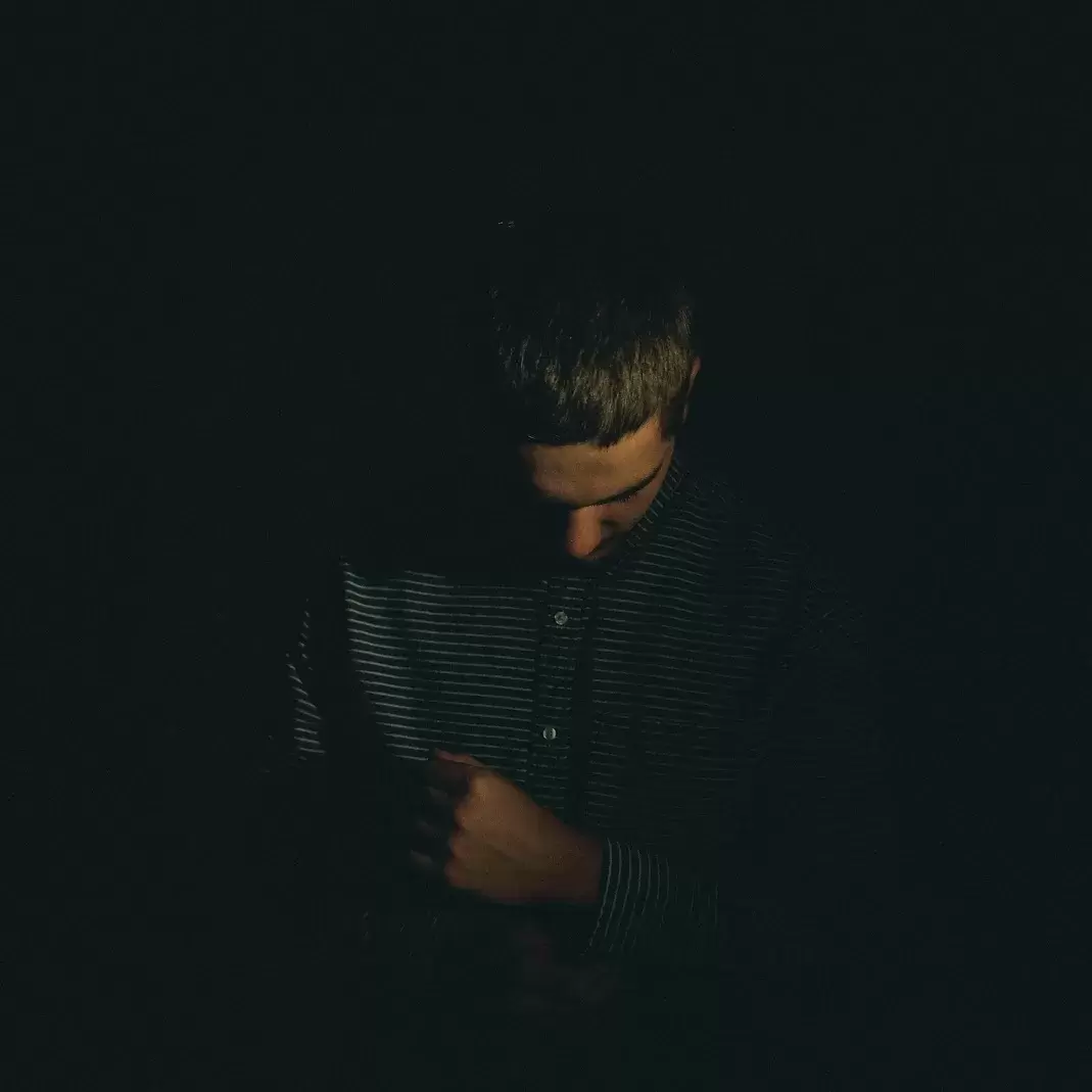 a person in a dark room looking down at their hands