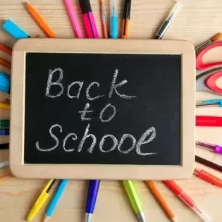 Small chalkboard surrounded by pens, pencils, scissors, etc. with Back to School writtenon it in chalk. 