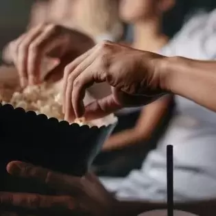 people eating popcorn from a popcorn bucket