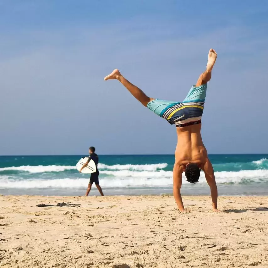 Muscular man doing cartwheels on the beach.
