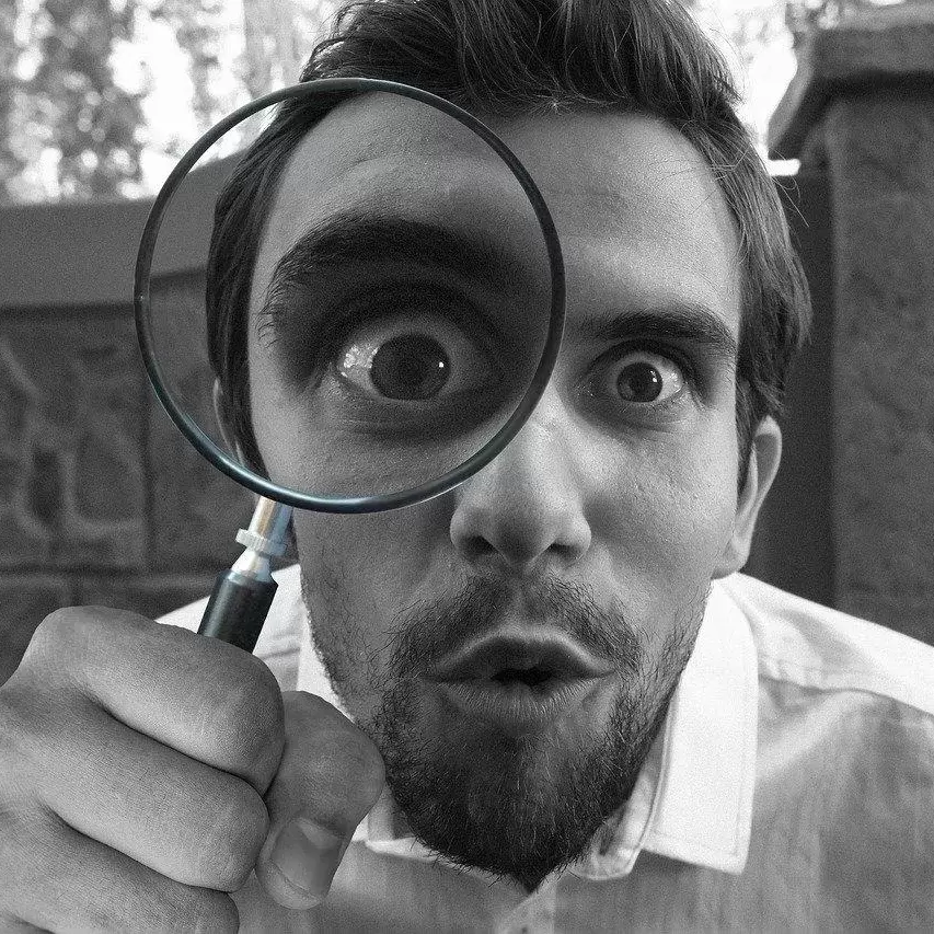 Man looking curiously through a magnifying glass