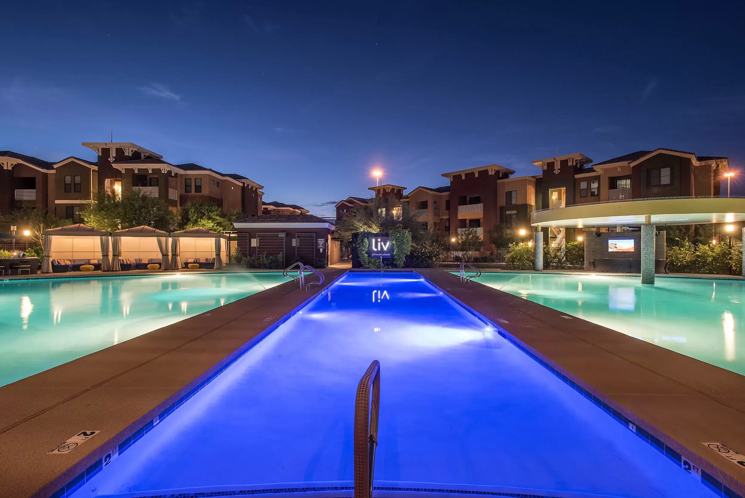 The pools lit up at night under a clear sky at Liv Ahwatukee.