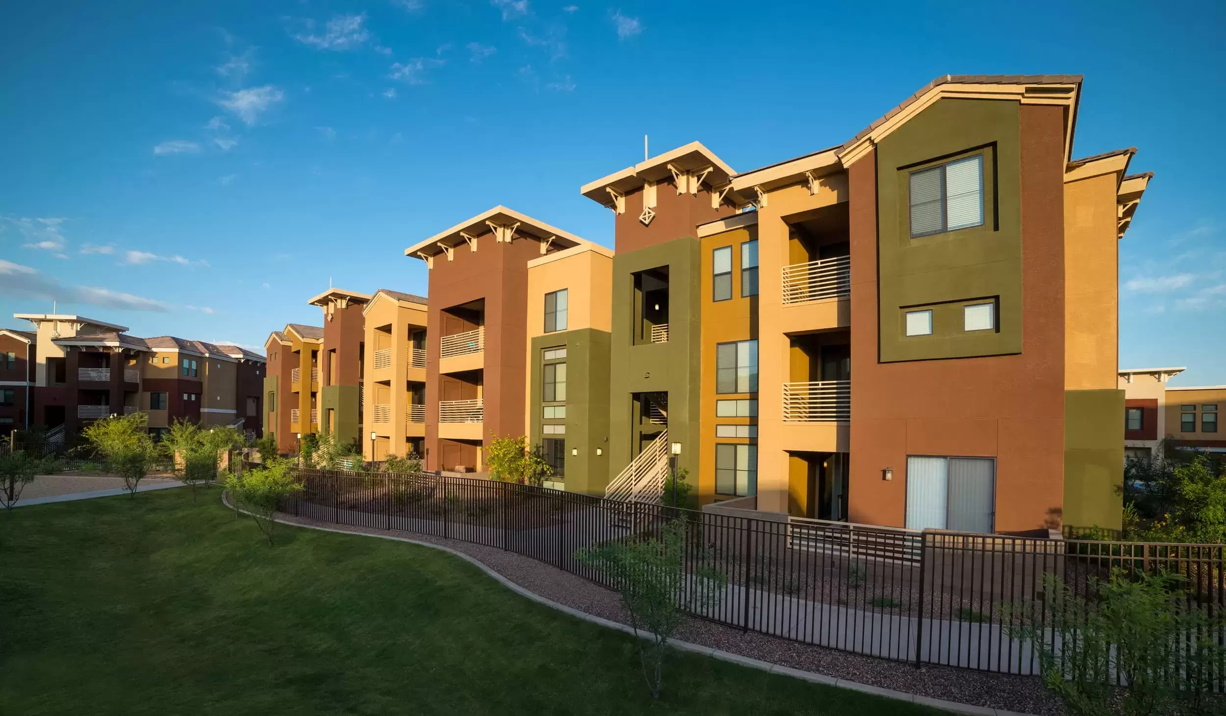 Grass, trees, and a sidewalk wrap around the exterior of the apartment buildings at Liv Ahwatukee.